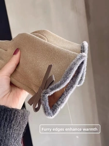 Close-up of beige velvet winter gloves with fluffy grey faux fur cuffs and a bow accent