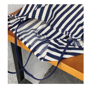 Detail of blue and white striped canvas tote bag showing heavy woven texture on a wooden bench