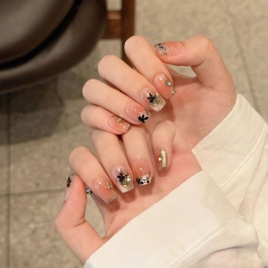 Detail of handmade press-on nails with black butterflies, gold foil, and crystals