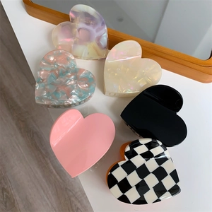 Colorful heart-shaped acetate hair claws in various patterns on a white background