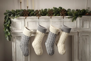 Close-up of grey and cream cable knit Christmas stockings hanging on a white fireplace mantle