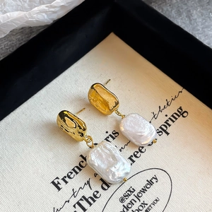 Detailed macro of vintage baroque pearl drop earrings on a minimalist canvas display