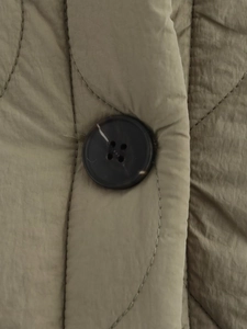Detail of olive green quilted jacket featuring marbled buttons and fine stitching texture