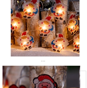 Détail de guirlandes LED Père Noël pailletées suspendues sur bouleau avec lueur chaude