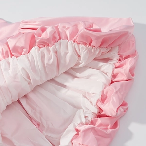 Detailed view of pink and white satin shorts with ruffled edges and silky pleated texture