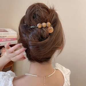 Detailansicht der bernsteinfarbenen Harzperlen auf einer Retro-Haarklammer für Frisuren