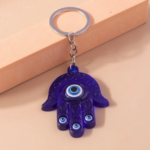 Detail of blue resin Hamsa Hand keychain with Evil Eye charms on pink geometric block