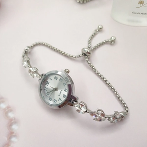 Détail d'une montre à quartz argentée sertie de strass sur fond rose élégant