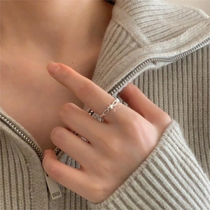 Close-up of minimalist silver chain link ring worn on finger with elegant knit background