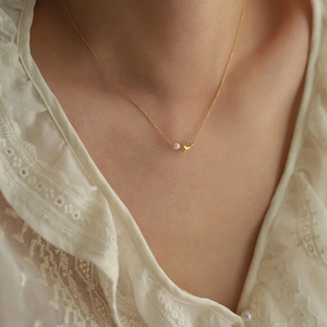 Détail d'un collier dauphin plaqué or 18K avec perle d'eau douce sur un mannequin