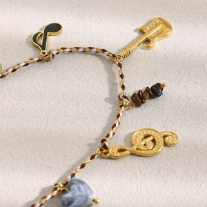 Detail of guitar pendant with rhinestones and music notes on woven cord necklace