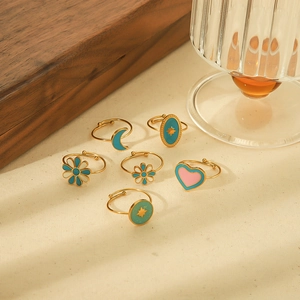 Detail of bohemian gold-plated steel rings with colorful enamel floral and moon designs