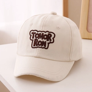 Close-up of brown 'TOMORROW' embroidery on beige cotton twill baseball cap for kids