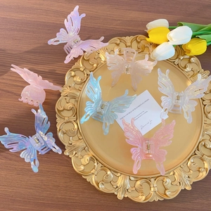 Iridescent acrylic butterfly hair claws in multiple colors on a golden vintage tray