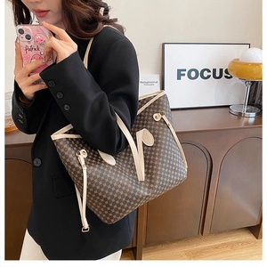 Detail of large brown geometric tote bag with cream handles shown on model shoulder