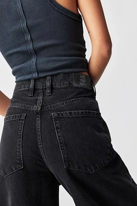 Detail of washed black denim jeans back pocket with vintage leather label and stitching