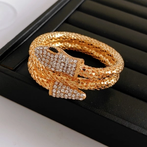 Macro shot of gold snake-shaped bangle with diamonds and scale textures in a jewelry box
