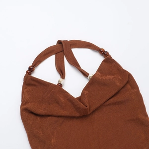 Detail of brown backless dress featuring textured fabric and beaded halter shoulder straps