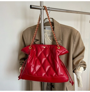 Detail of red quilted leather chain bag showing golden buckle and fashion typography