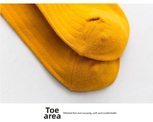 Close-up of yellow knitted cotton socks featuring vertical ribbed texture and flat-seam toe