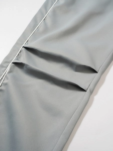Detailed view of grey technical pants featuring white piping and high-quality twill fabric