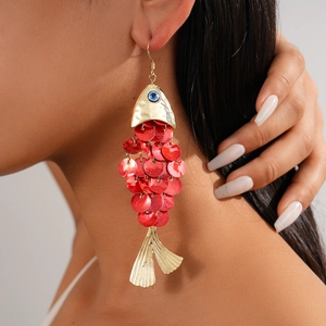 Detailed view of fish-shaped earrings with red scales and metallic gold finish on ear