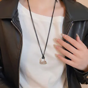 Minimalist square metal pendant necklace with silver finish and black cord worn by a model