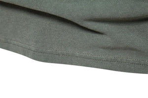 Detail of double-needle stitching on the hem of a green cotton pique polo shirt
