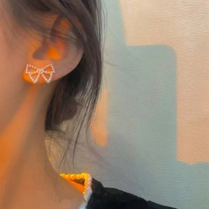 Elegant pearl bow stud earrings for women with minimalist aesthetic on model ear