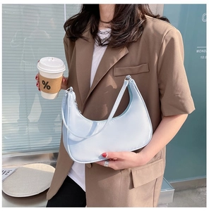 Model wearing light blue nylon crescent moon shoulder bag in a bright modern setting
