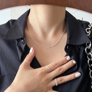 Close-up of minimalist S925 sterling silver necklace and rings set on female model