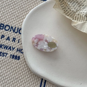 Detail of pink marble acetate hair clip with golden metal accent on a display tray