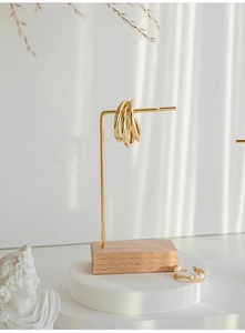 L-shaped gold metal jewelry stand with wooden base displaying elegant gold hoop earrings