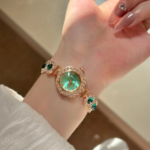 Detail der roségoldenen Armbanduhr mit grünem Zifferblatt und funkelnden Strasssteinen