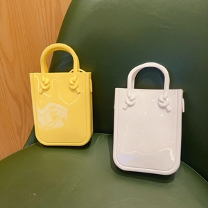 Detailed view of yellow and white PVC jelly bags on a leather chair with rope handles