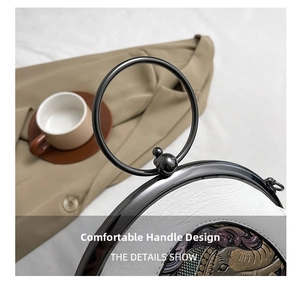Detail of white leather bag with black metal ring handle and embossed floral patterns