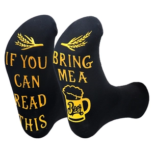 Detail view of black cotton socks with anti-slip yellow text Bring Me A Beer on soles