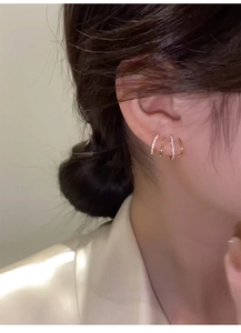 Close-up of golden multi-layer earrings with sparkling crystals on female model