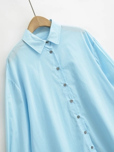 Detailed close-up of light blue long-sleeve cotton shirt with buttons and lapel collar