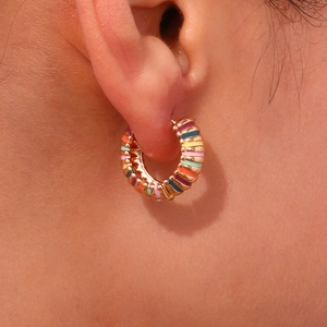 Macro view of rainbow enamel stripes on a gold-plated stainless steel hoop earring