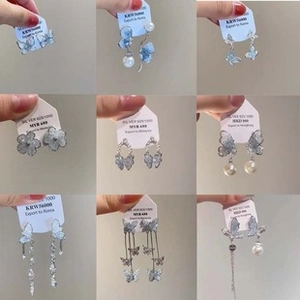 Macro view of blue flower hair pins and butterfly earrings with pearls and silver tassels