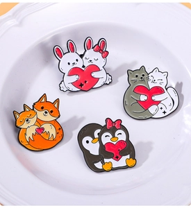 Detail view of cute enamel pins featuring cats, rabbits, foxes and penguins holding hearts