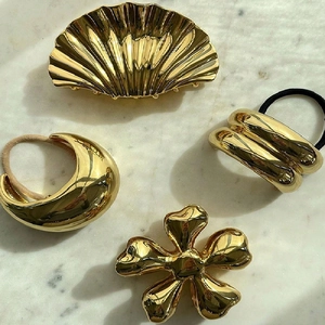 Elegant gold metal flower and shell hair claw clips set on marble background