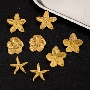Detailed view of golden flower and starfish stainless steel stud earrings set on black texture