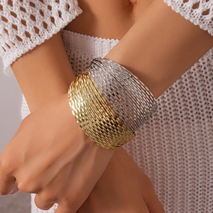 Detail of layered gold and silver wide metal bangles with textured diamond-cut surface