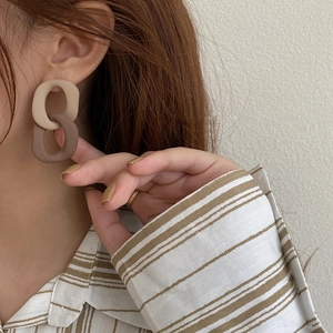 Minimalist beige and brown acrylic geometric double-hoop earrings worn by a model
