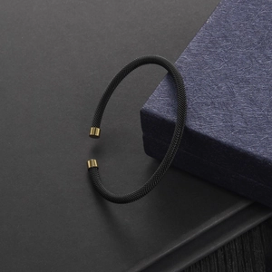 Close-up of black mesh braided cable bracelet with gold tips and blue gift box