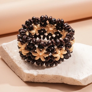 Détail du tissage de perles en bois noir et blanc formant des motifs ethniques de fleurs