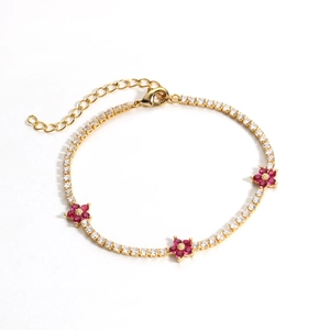 Detail of gold tennis bracelet featuring white zircons and pink flower charms with lobster clasp