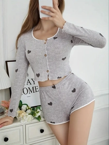 Close-up of grey knit pajama set featuring black heart print and ruffles with wood buttons